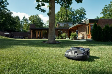 Mähroboter in einem Garten mit einem modernen Haus im Hintergrund.