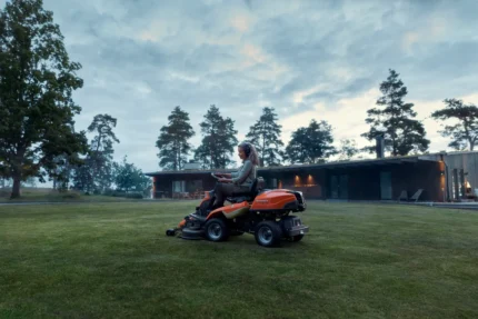 Eine Person, die mit einem Rider-Rasenmäher in einer Gartenumgebung den Rasen mäht.