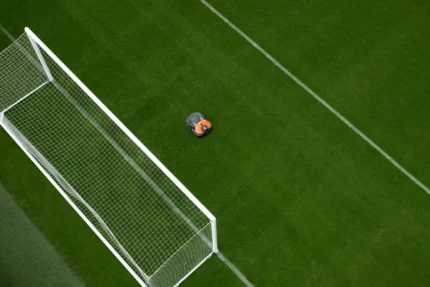 Mähroboter, der auf einem Fußballfeld in der Nähe eines Torpfostens arbeitet.