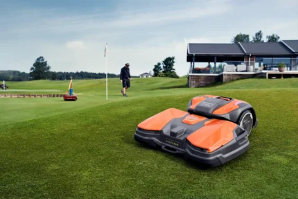 Ein Mähroboter, der auf einem Golfplatz betrieben wird, während eine Person in der Nähe spazieren geht.