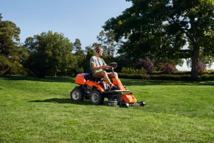 Eine Person, die mit einem Aufsitzmäher in einem Garten den Rasen mäht.