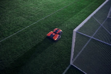 Mähroboter, der auf einem Fußballfeld in der Nähe eines Torpfostens arbeitet.